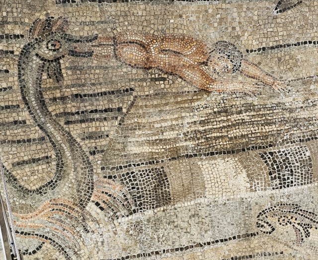 An aquatic sea monster with a goatee and fan-like flippers regurgitates a nude mosaic man.